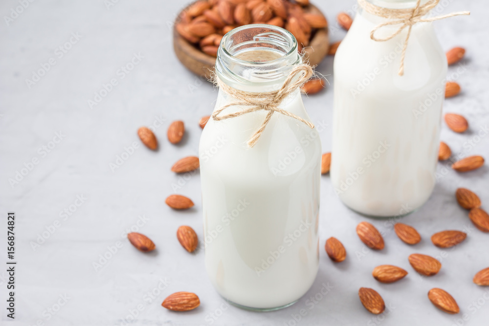 Almond milk in bottles with almonds on background, horizontal, copy space Almond milk in bottles with almonds on background, horizontal, copy space