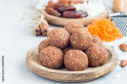 Healthy homemade paleo energy balls with carrot, nuts, dates and coconut flakes, on wooden plate, horizontal, copy space
