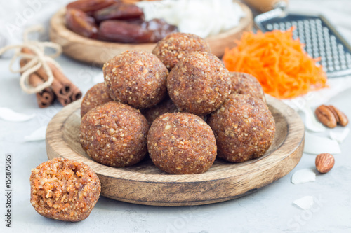 Healthy homemade paleo energy balls with carrot, nuts, dates and coconut flakes, on wooden plate, horizontal