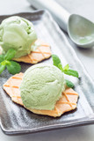 Matcha green tea ice cream balls served with waffles on black plate, vertical