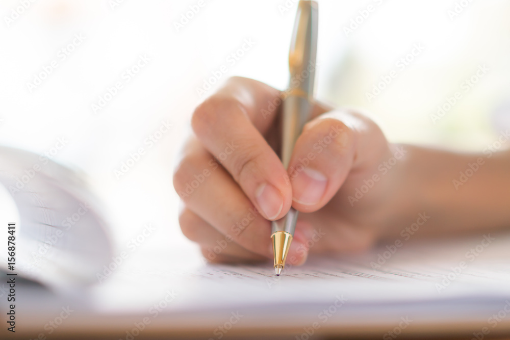 Hand with pen over application form Hand with pen over application form