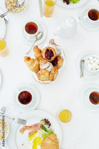 Tasty buns, tea, orange juice and other food on served table