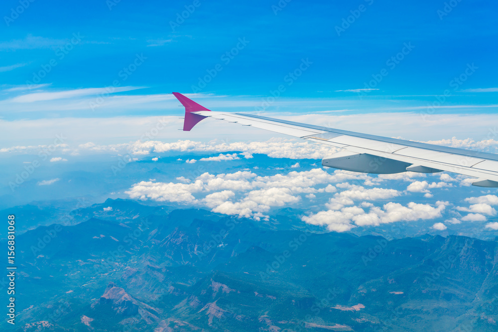 Wing of an airplane flying above the clouds . Wing of an airplane flying above the clouds .