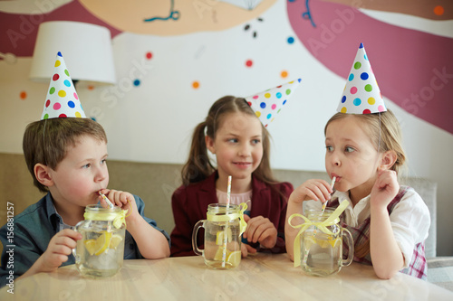 Canvas Print Thirsty kids drinking fresh lemonade through straw