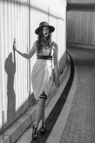 Bild auf Leinwand Young beautiful sexy woman wearing trendy outfit, white dress, black hat and leather swordbelt