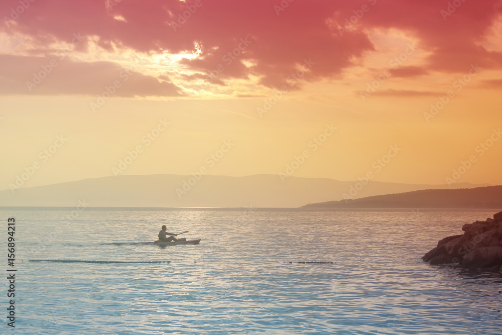 Silhouette of a man in a boat canoe  in the sea In bright saturated colors. Seascape. Minimalism