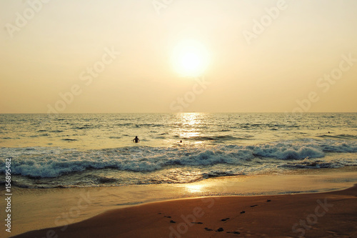 Sunset in India. Tropical beach and peaceful ocean. Aged photo. Tourists enjoy the sea on sunset.