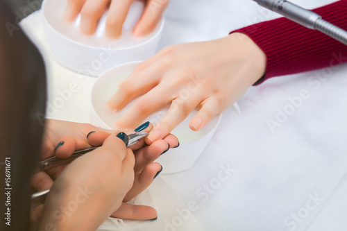 Hands of the girl in the baths with water during a manicure, cleansing the cuticle