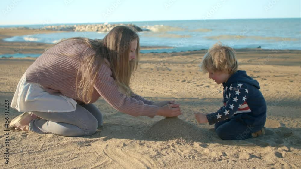 Mom and son playing with sand on the beach. Mom and son playing with sand on the beach.