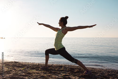 fitness mixed race asian woman in yoga pose on the morning beach, beautiful fit woman practice fitness exercise on sand, morning sea or ocean background
