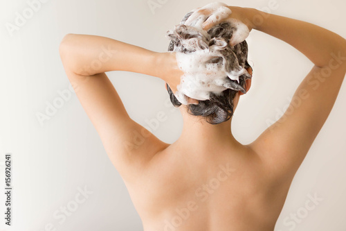 Isolated back shot of a sexy model shampooing her hair with lots of suds.