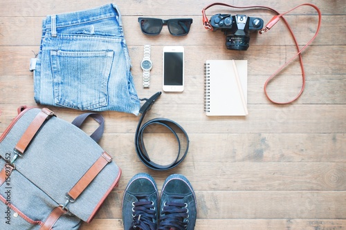 Overhead shot of essentials for traveler. Outfit of young man traveler, camera, mobile device, sunglassses. Travel concept