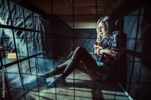 Frightened blond woman in the dark cage.