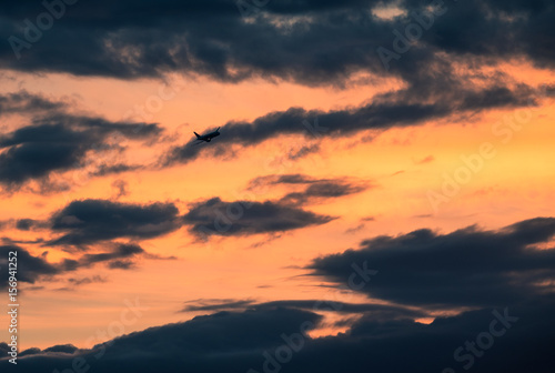 Airplane flying against colorful sunset sky at spring evening © Jani Riekkinen
