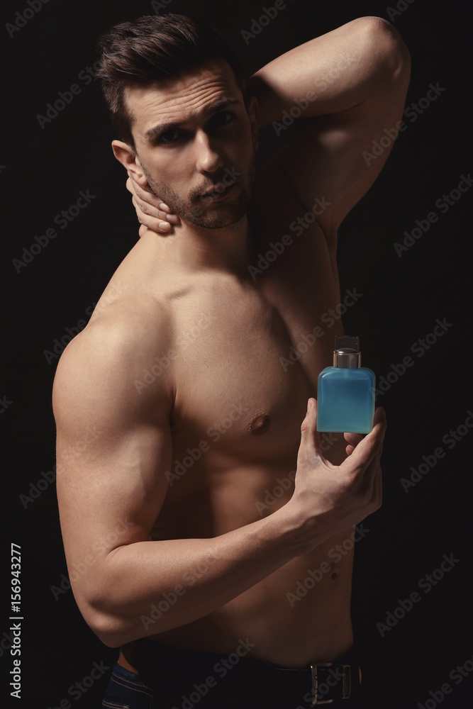 Handsome man using perfume on black background Handsome man using perfume on black background
