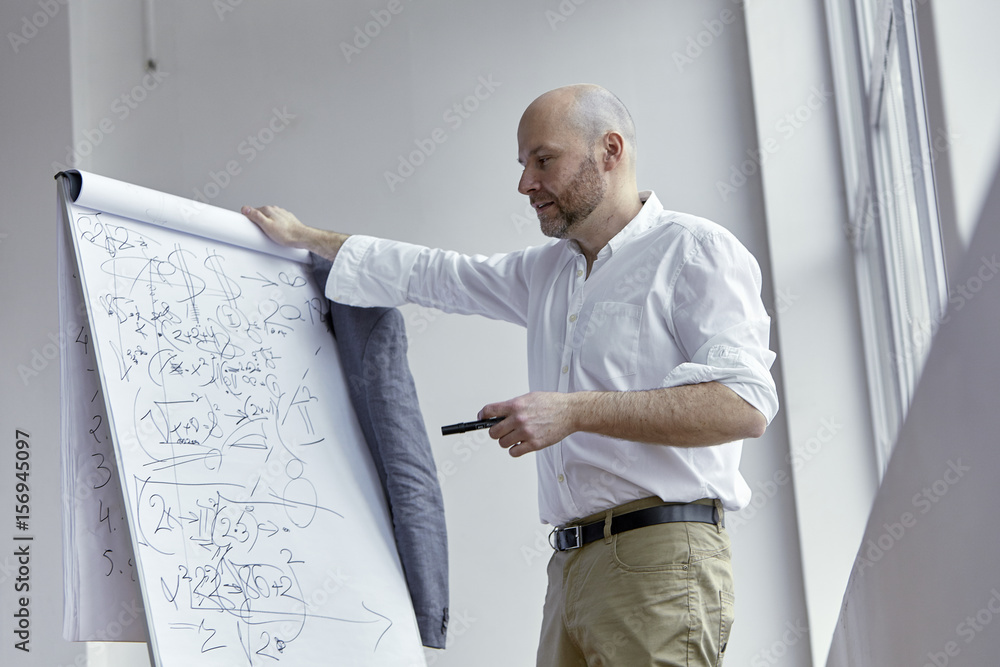 Fototapeta premium Bald Man Pointing at the Board With a Marker
