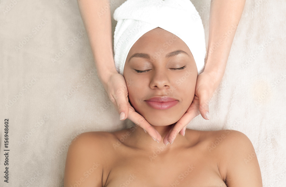 Beautiful African-American girl having massage in spa salon Beautiful African-American girl having massage in spa salon
