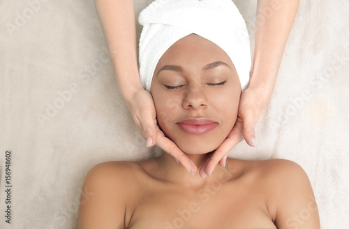 Beautiful African-American girl having massage in spa salon