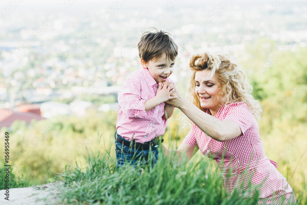 Happy mother and son walking on the hill in summer time. Mother and child hiking at sunset. Boy pointing at something distant. Summer vacation in mountains. Happy mother and son walking on the hill in summer time. Mother and child hiking at sunset. Boy pointing at something distant. Summer vacation in mountains.