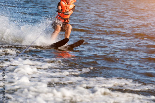 Woman riding water skis closeup. Body parts without a face. Athlete water skiing and having fun. Living a healthy lifestyle and staying active. Water sports theme. Summer by the sea