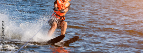 Woman riding water skis closeup. Body parts without a face. Athlete water skiing and having fun. Living a healthy lifestyle and staying active. Water sports theme. Summer by the sea. Banner for