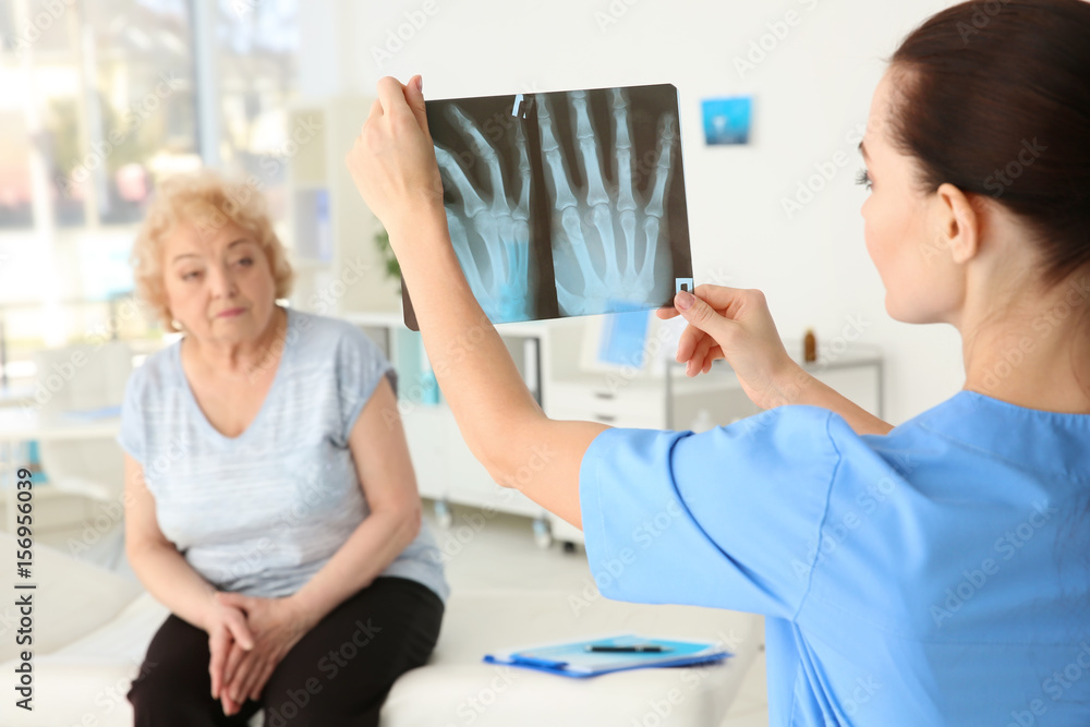 Female orthopedist examining senior woman in clinic Female orthopedist examining senior woman in clinic