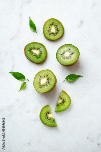 Kiwis flat lay on a marble background. Group of sliced and whole kiwi fruits viewed from above. Top view