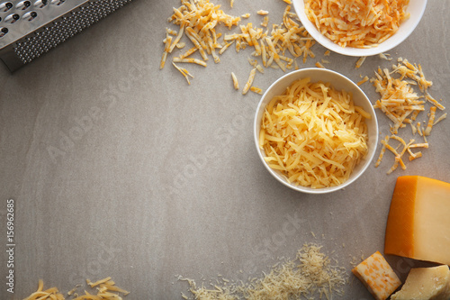 Bowls with delicious cheese and grater on light background