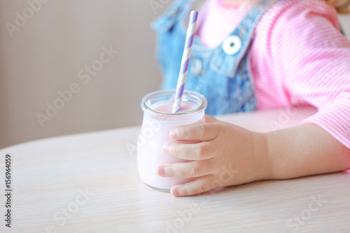 Cute little girl with yogurt at home, closeup