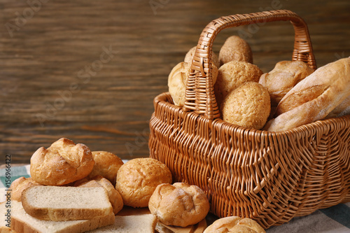 Basket with different bread on wooden background