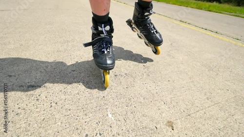 Mans legs roller skating on the asphal. Close up view to quick movement of inline boots.