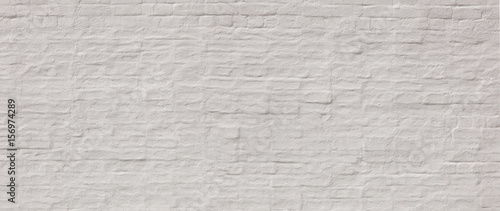 Whitewashed painted wide old brick wall with plaster texture. Background for text or image. 