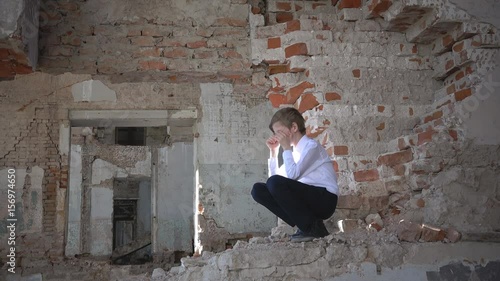 An orphan boy, a schoolboy crying in a ruined building after the war, lost, fear, loneliness