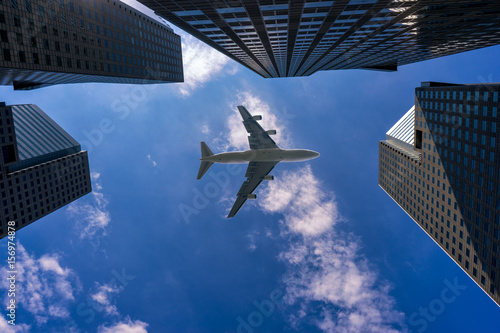 Commercial airplane flying over modern building in Singapore city