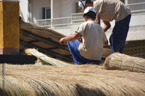 obreros reparando un tejado de paja
