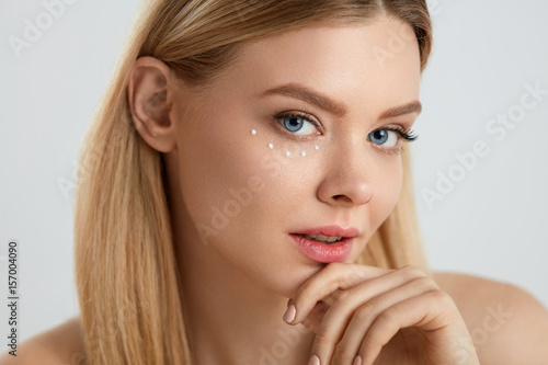 Facial Care. Woman With Drops Of Cosmetic Cream Under Eye
