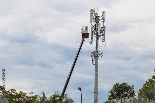 Two workers on crane installing mobile network telecommunication antenna