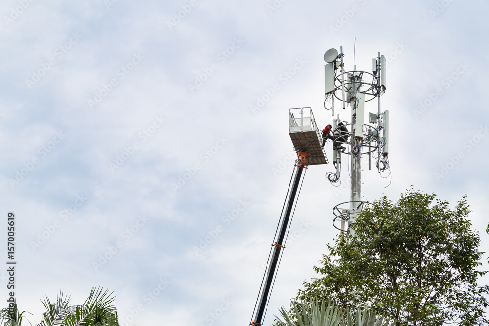 Two workers on crane installing mobile network telecommunication antenna Two workers on crane installing mobile network telecommunication antenna