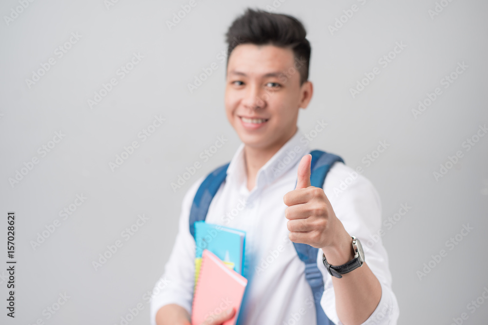 Asian male student making a thumb up sign isolated on white background Asian male student making a thumb up sign isolated on white background