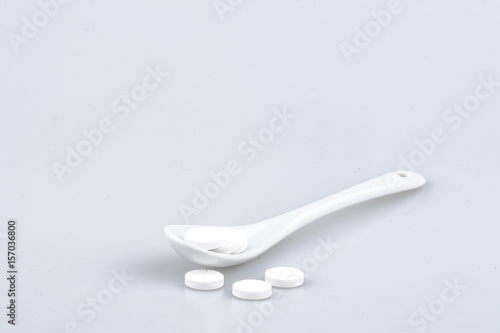 White pills on spoon isolated on white