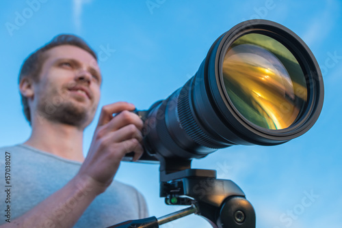 The man work with the camera against the blue sky background