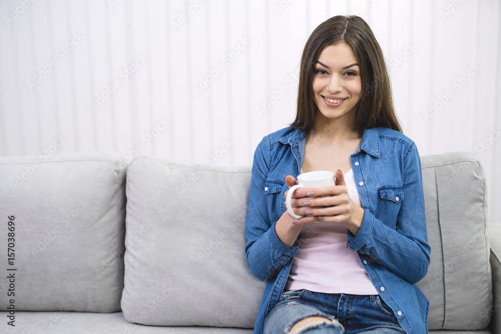The beautiful woman hold a cup of coffee on the sofa