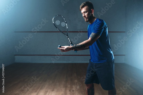 Male squash player training on indoor court