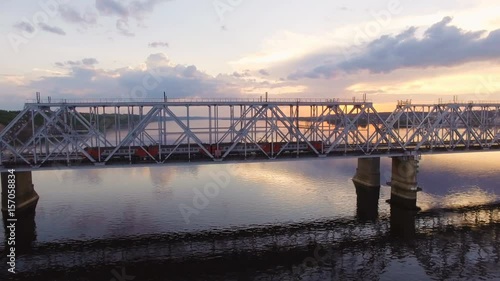 Railway bridge across the Volga river, which goes on passenger train. Aerial view photo