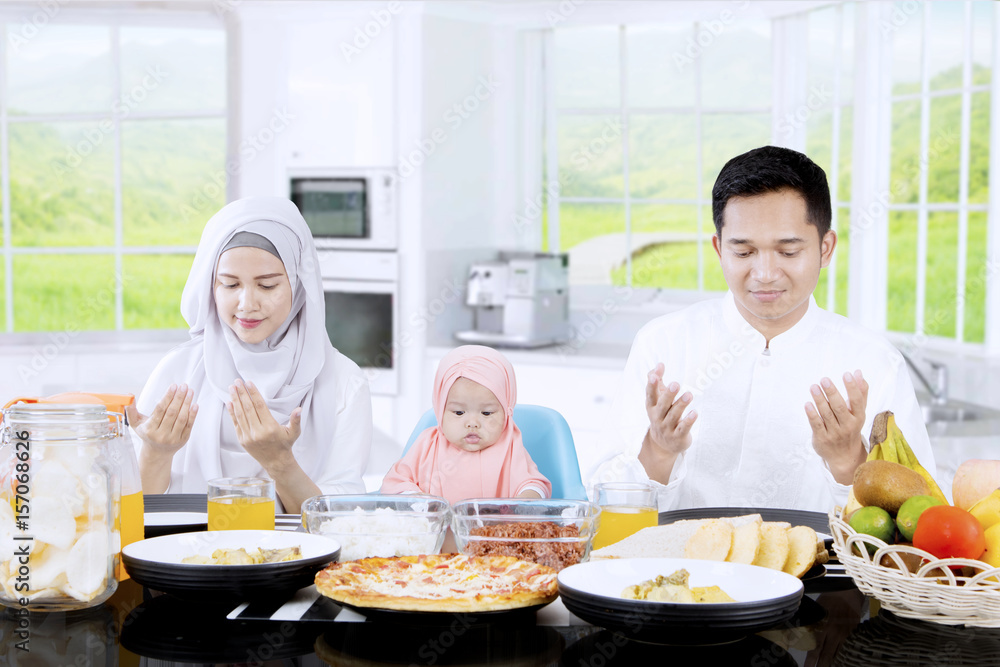Happy family praying together in kitchen