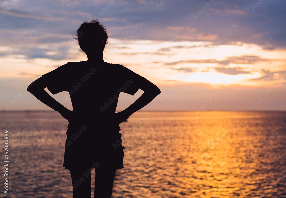 The girl silhouette at the sea with sunset sky.