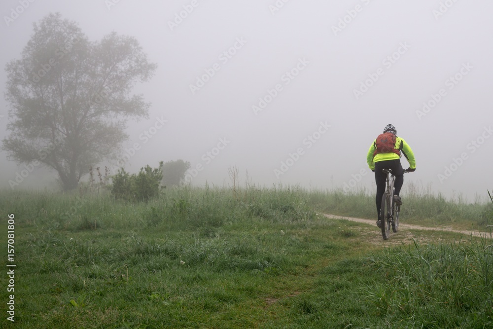 Cyclist on a meadow during foggy morning. Slovakia