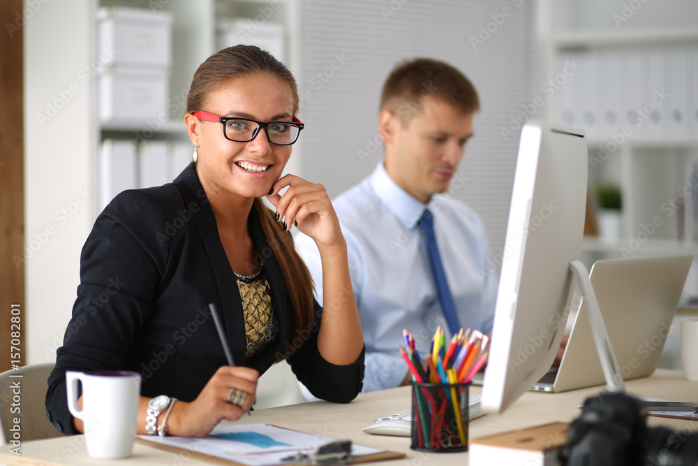Young woman working in office, sitting at desk with folder