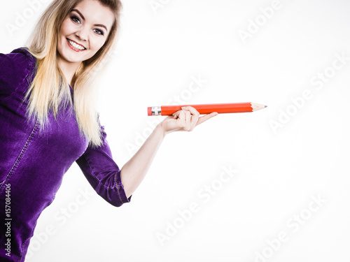 Smiling woman holds big pencil in hand