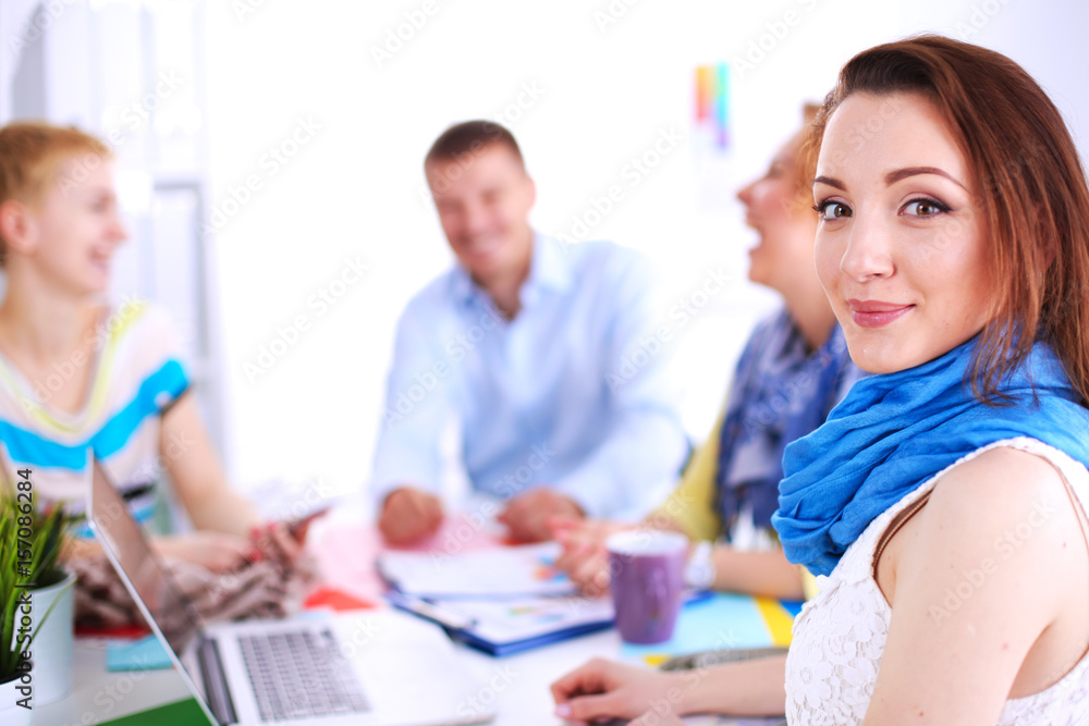 Portrait of attractive female designer sitting on desk in office Portrait of attractive female designer sitting on desk in office